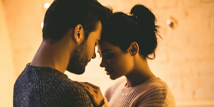 a man and woman standing next to each other in front of a wall with lights