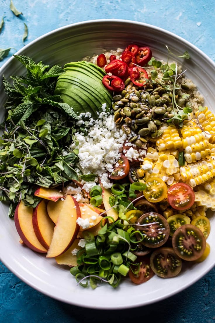 a white bowl filled with lots of different types of food on top of a blue table