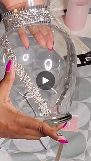 a woman is holding a clear glass bowl with silver decorations on it and her nails are painted pink