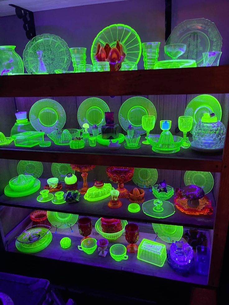 neon green dishes and plates are on display in a dark room with purple lighting behind them