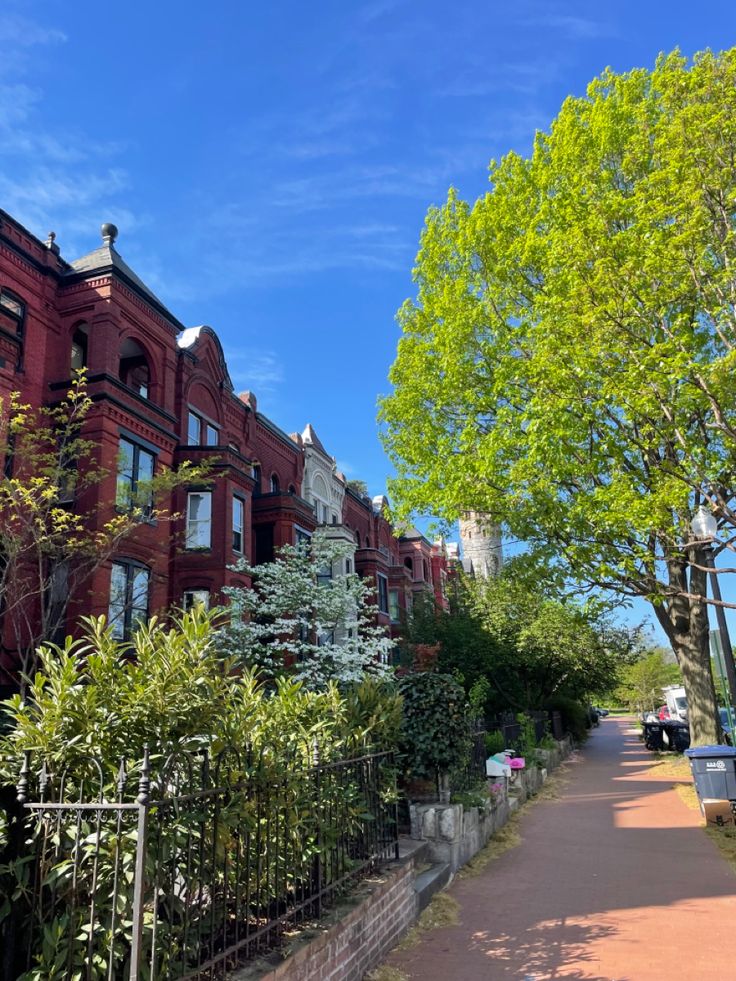 the sidewalk is lined with red brick buildings and trees on both sides of the street