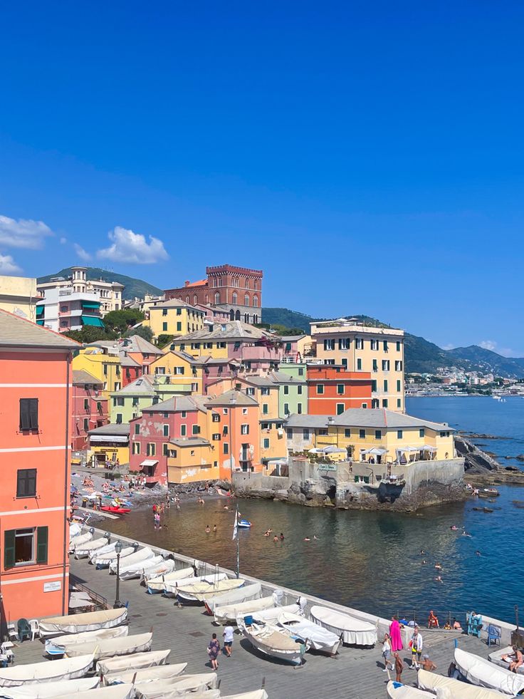 boats are lined up on the shore in front of colorful buildings