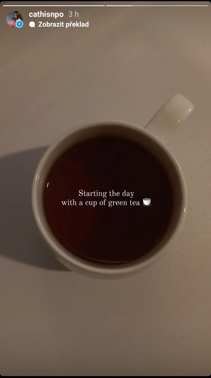 a cup of coffee sitting on top of a table next to a cell phone with the caption starting the day with a cup of green tea