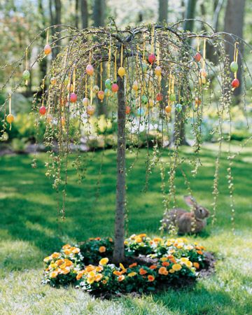 an apple tree in the middle of a garden with yellow and orange flowers around it