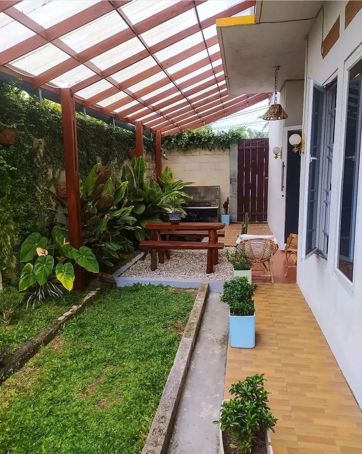 an outdoor patio area with wooden flooring and green plants on the side of it