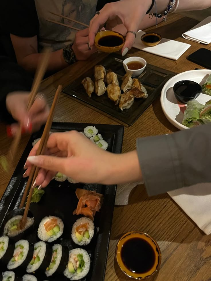 people are eating sushi and chopsticks at a table