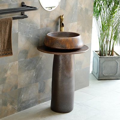 a bathroom sink sitting under a mirror next to a potted plant