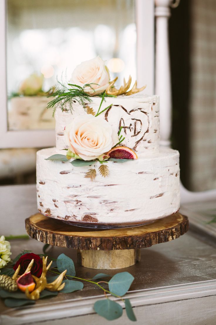 a white wedding cake with flowers on top sitting on a table next to a mirror