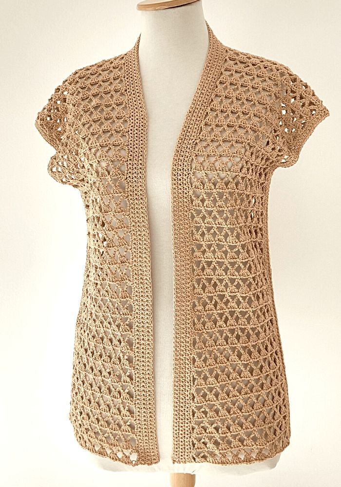 a white mannequin wearing a beige crochet cardigan on a dummy