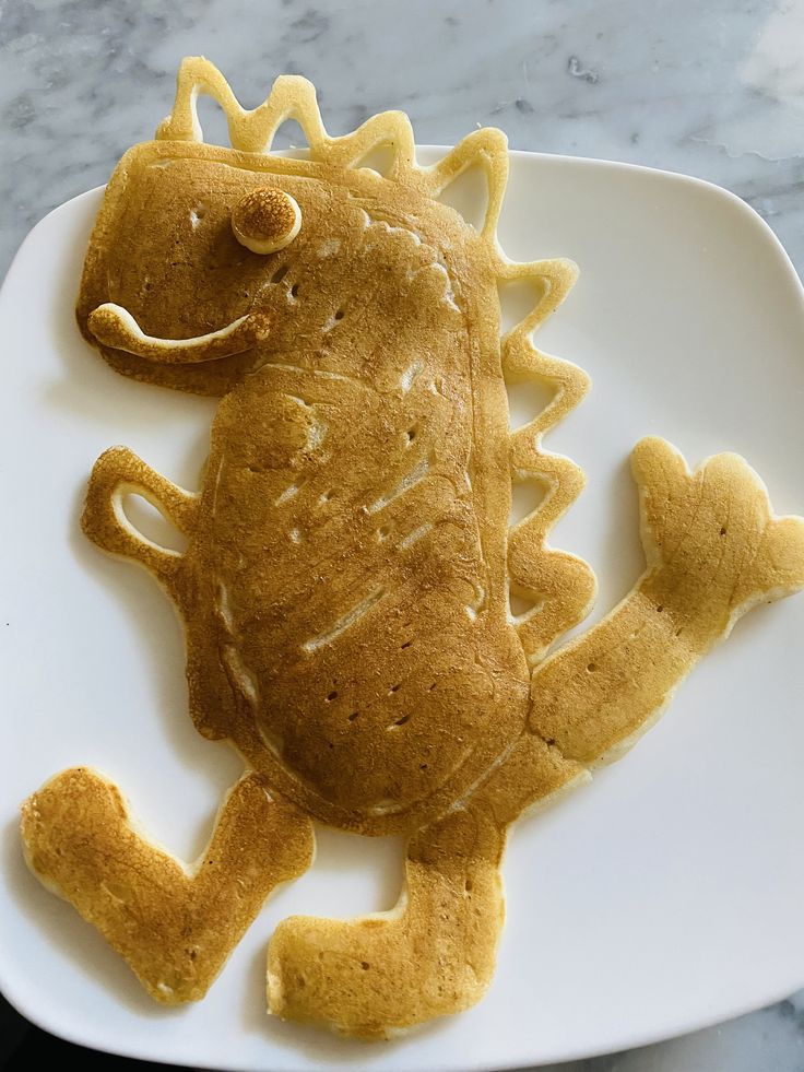 a white plate topped with a cookie shaped like a lizard on it's side