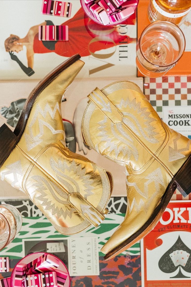 a pair of gold cowboy boots sitting on top of a table next to other items