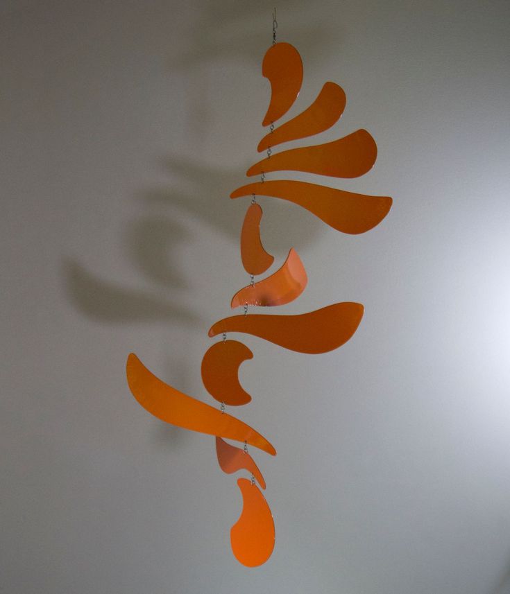 an orange wind chime hanging from the side of a white wall in a room