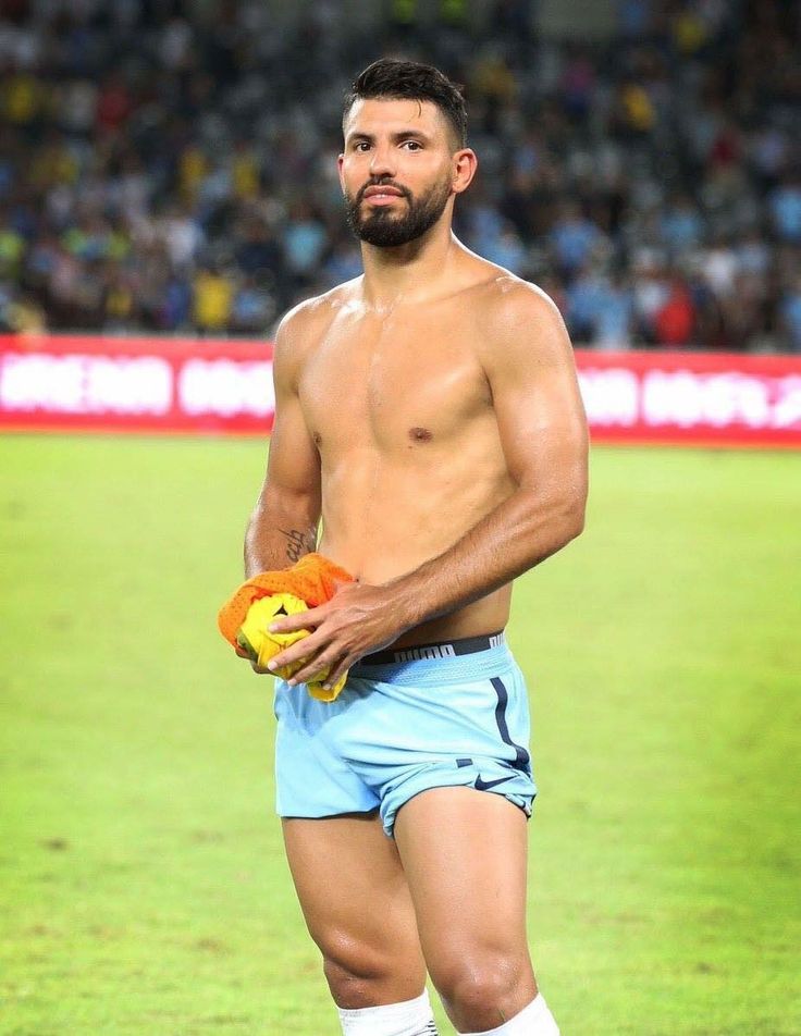 a shirtless man holding a stuffed animal in his hand on the field at a soccer game