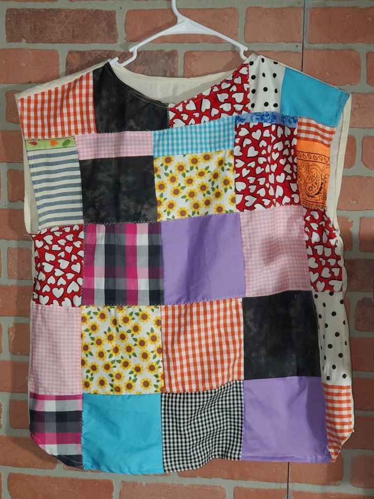 a colorful patchwork shirt hanging on a brick wall