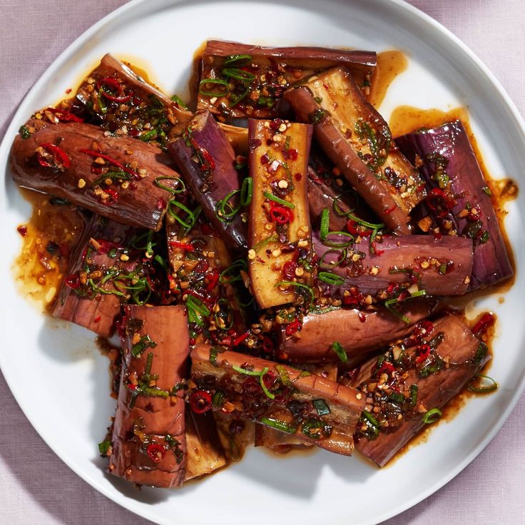 a white plate topped with sliced up meat covered in sesame seeds and garnishes