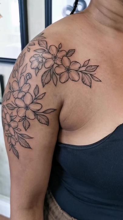 a woman's breast with flowers on her left arm and the top half covered in black ink