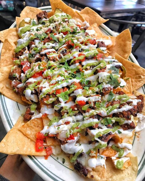 a plate filled with nachos covered in cheese and sauce