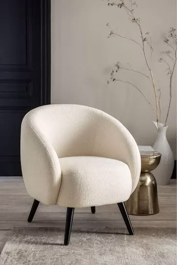 a white chair sitting on top of a wooden floor next to a vase filled with flowers