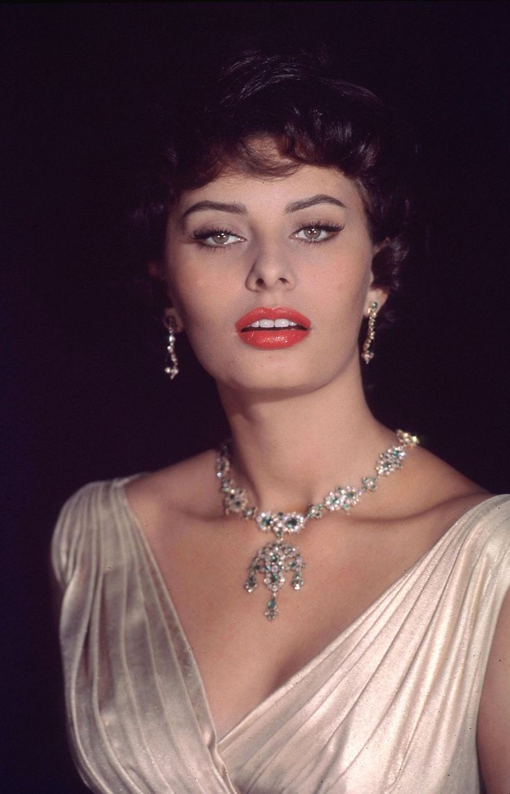 a woman in a white dress with jewelry on her neck