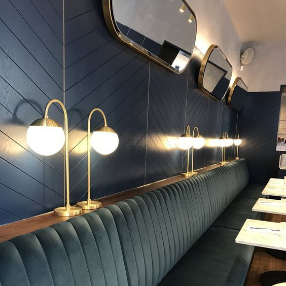 an empty restaurant with blue booths and gold fixtures on the wall, along with white tables