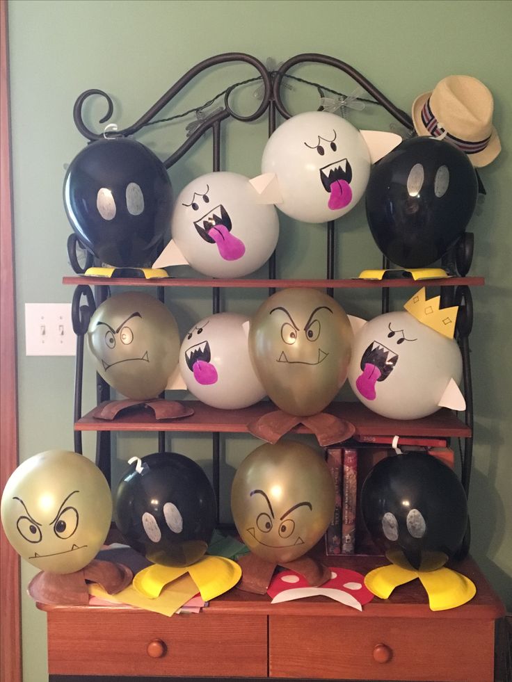 many balloons with faces on them are sitting on a shelf next to a hat rack