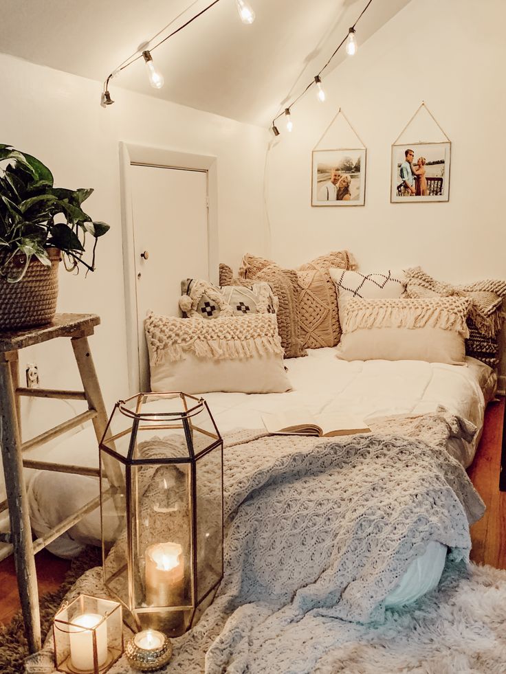 a bed with pillows and blankets on top of it next to a table filled with candles