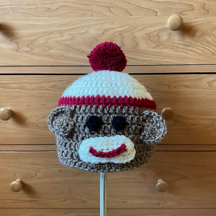 a crocheted sock monkey hat on top of a stick