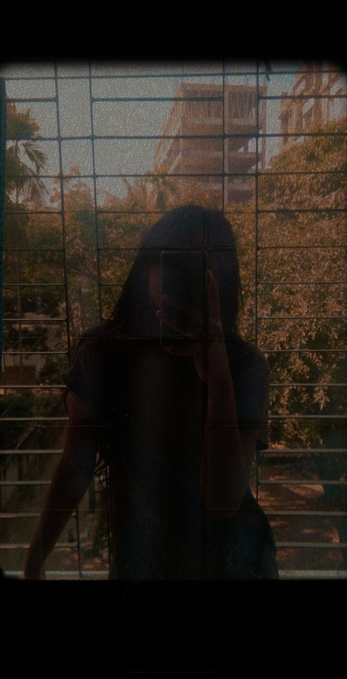 a person taking a photo in front of a caged window with their cell phone