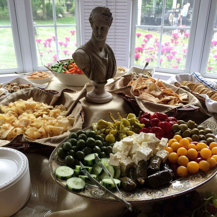 an assortment of food on a table with a statue in the window sill behind it