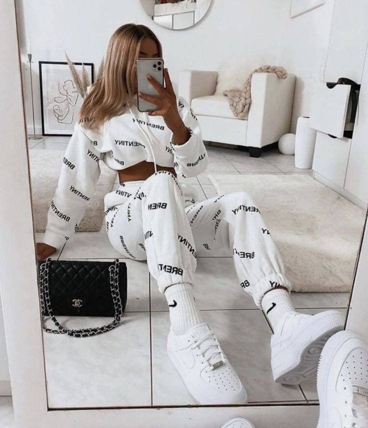 a woman sitting on the floor in front of a mirror taking a selfie with her cell phone