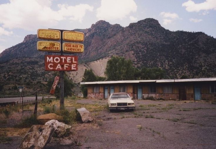 an old motel sits in the middle of a desert area with mountains in the background