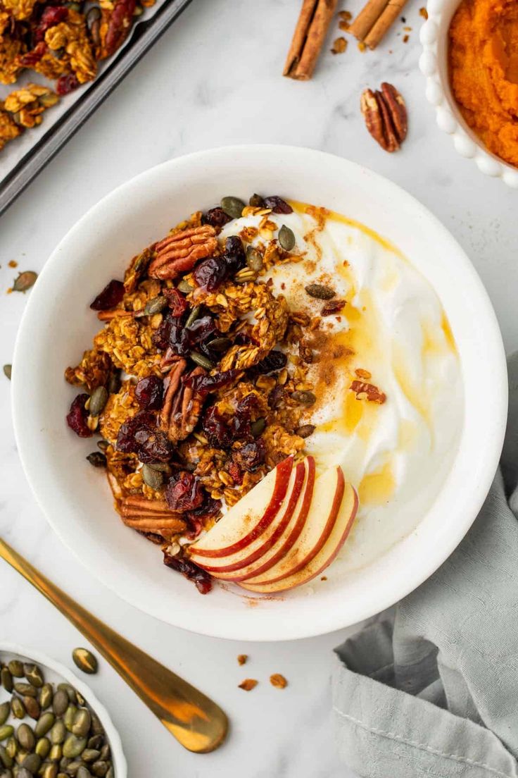 a bowl filled with yogurt, granola and apples