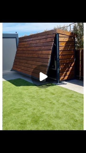 a large wooden structure sitting on top of a lush green field next to a garage