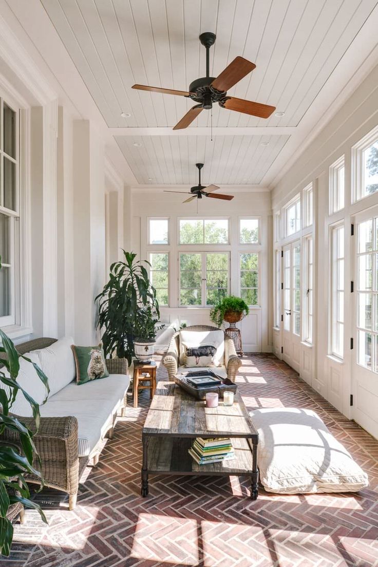 the sun shines through the windows in this living room with white walls and brick flooring