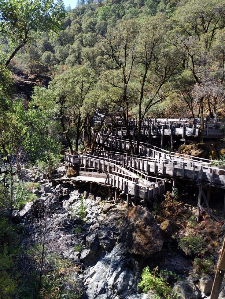 an old wooden bridge is surrounded by trees and rocks