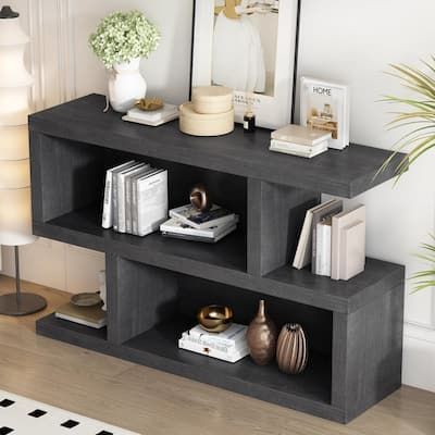 a black shelf with books and vases on it next to a lamp in a living room