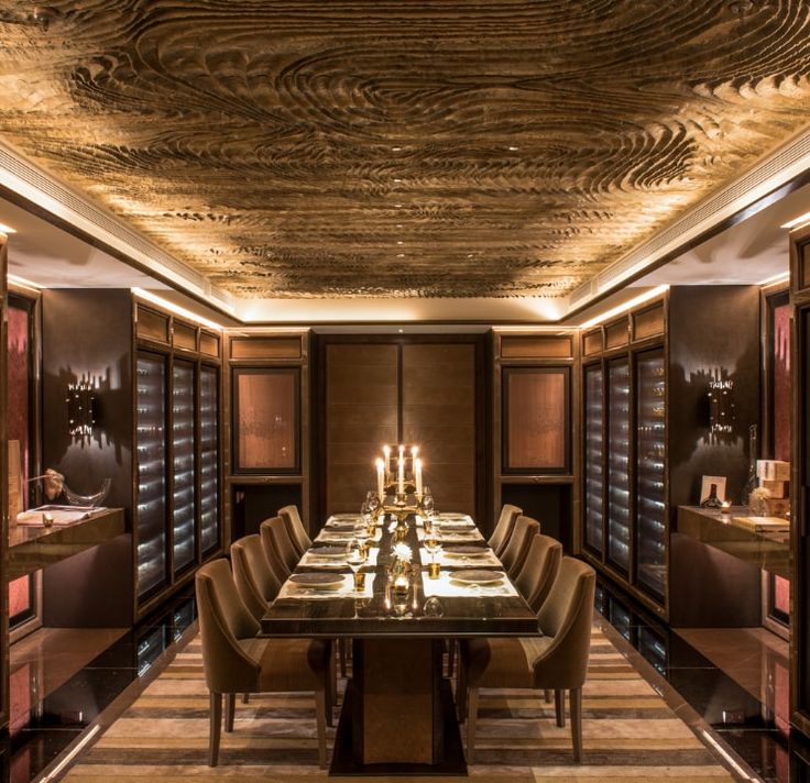 a long table with chairs and candles on it in the middle of a dining room