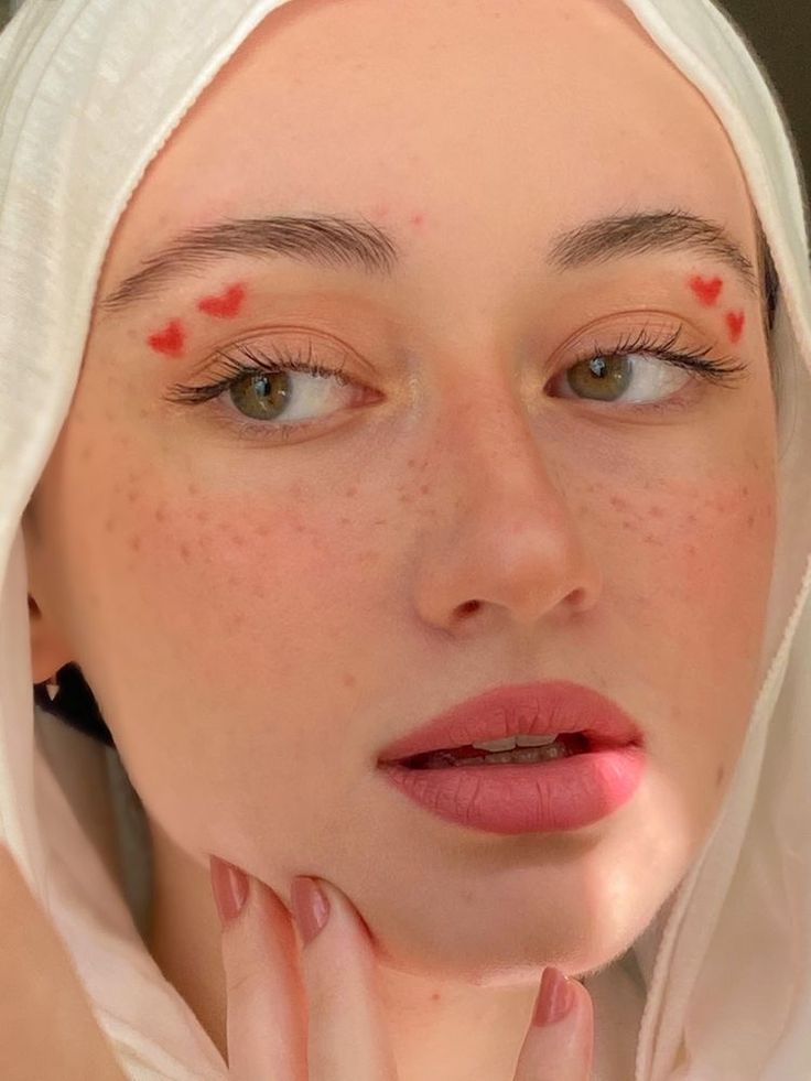 a woman with freckles on her face is looking at the camera while wearing a white head scarf