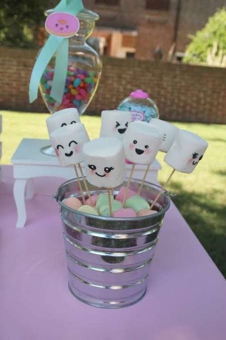 marshmallows in a glass bowl on a table with other treats and candies