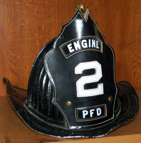 a black fireman's helmet with the number 2 on it sitting on a shelf