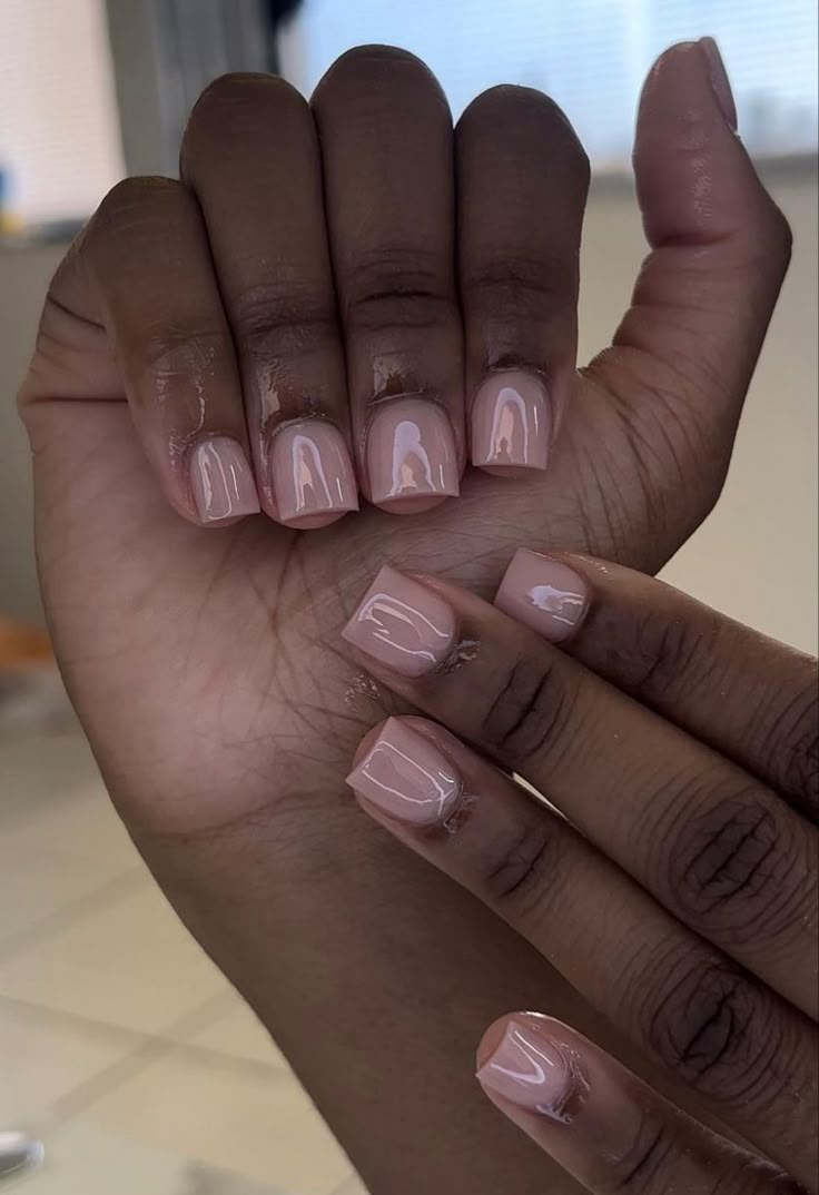 a woman's hand with pink and white manicures on it, holding up her nails