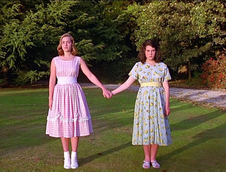 two young women holding hands while standing in the grass