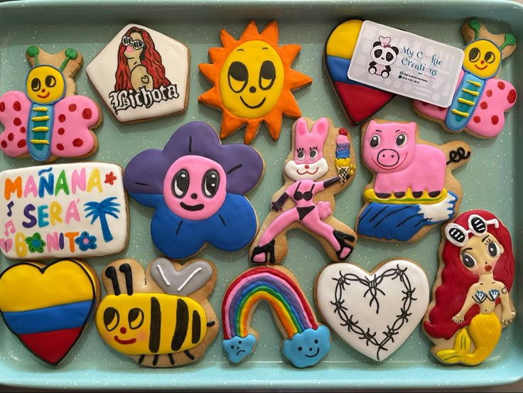 decorated cookies in the shape of animals and other things on a blue tray with white writing