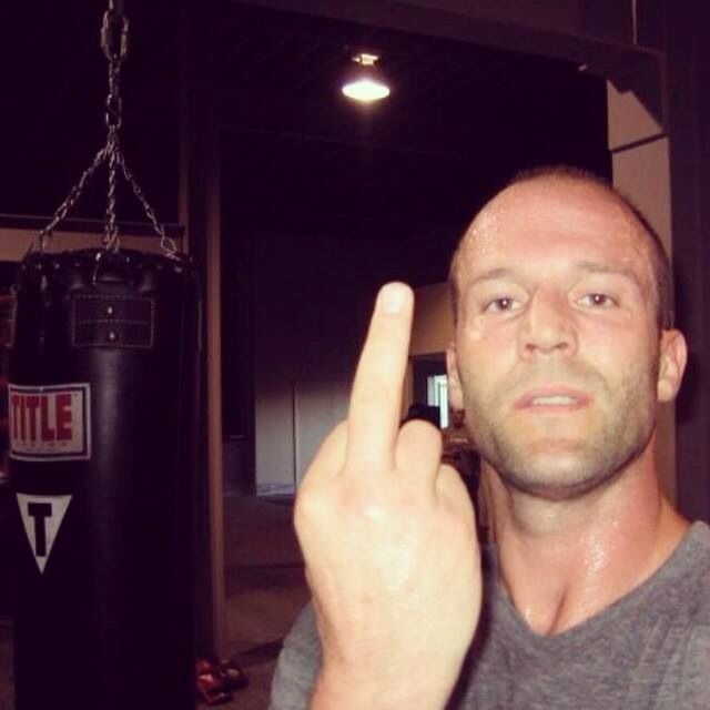 a man pointing at the camera in front of a punching bag with his finger up