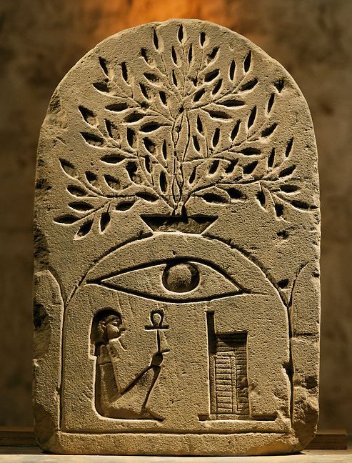 an ancient stone carving depicting the eye of horus in front of a tree with leaves on it