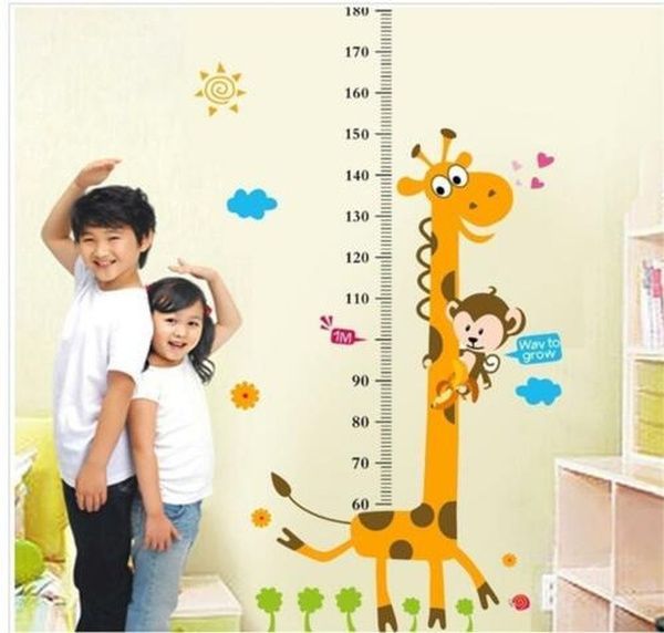 two children standing next to each other in front of a growth chart wall decal