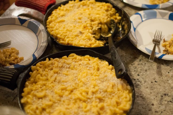 three skillets filled with macaroni and cheese on top of a marble counter