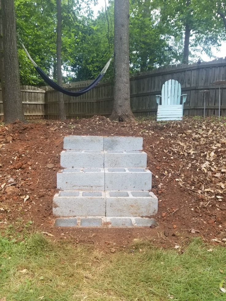 a cement block sitting in the middle of a yard next to a blue lawn chair