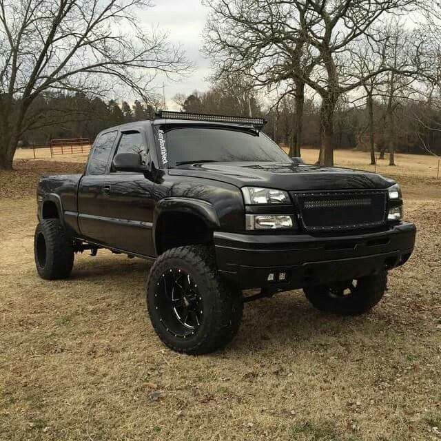 a black truck parked in the middle of a field