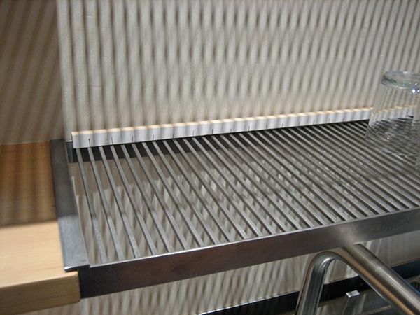 stainless steel conveyor belt with glass bottle on top and metal handrail in front